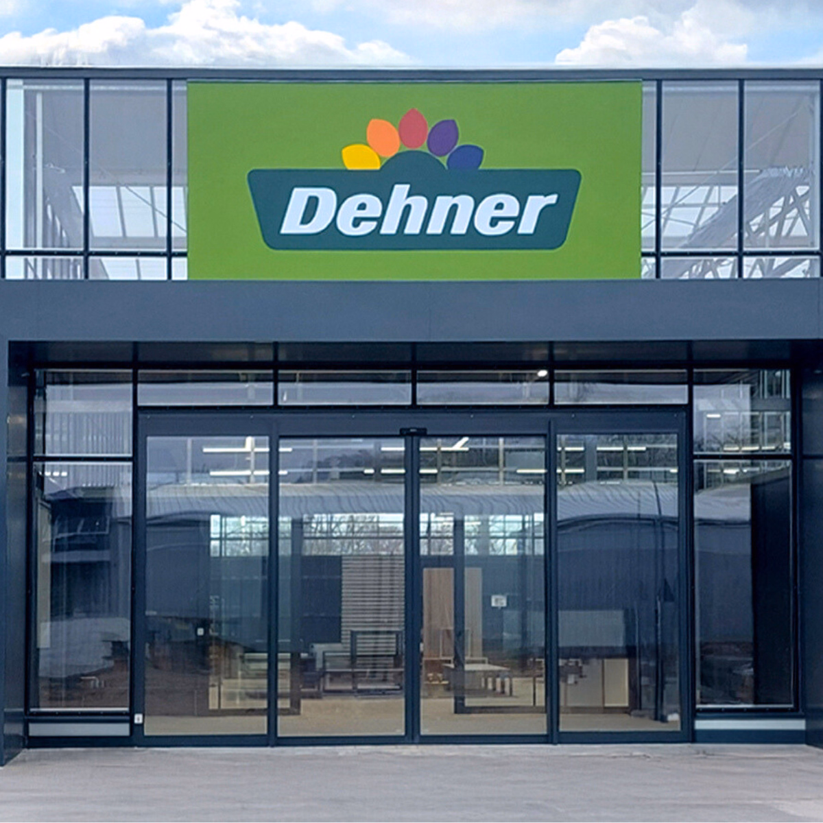 Wejście do centrum ogrodniczego Dehner w w Neumarkt in der Oberpfalz z widocznym logo nad szklaną fasadą. 