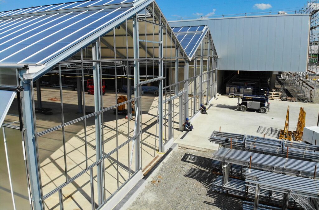 Zaawansowany montaż ścian szklanych w części frontowej centrum ogrodniczego, przygotowanie pod instalację fasady.