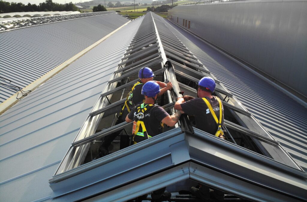 Prace montażowe na dachu, instalacja elementów systemu otwierania dachu typu cabrio przez ekipę techniczną.