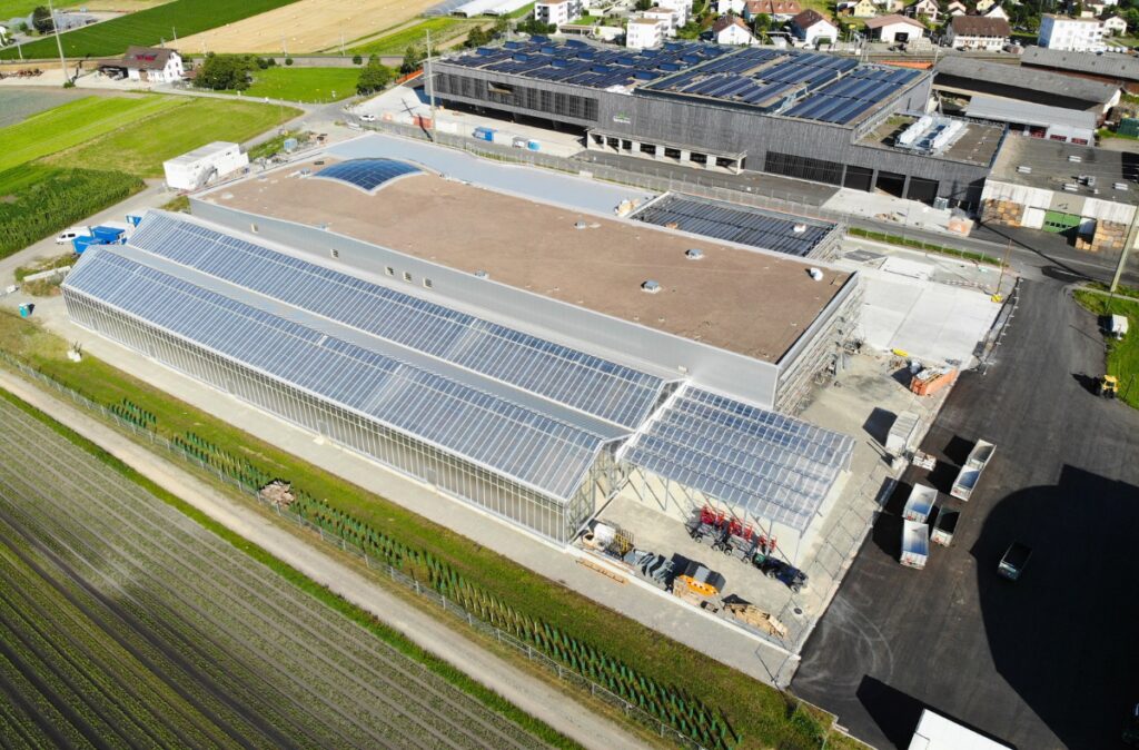 Widok z lotu ptaka na ukończoną konstrukcję centrum ogrodniczego Blumenbörse wraz z przeszkloną częścią frontową i dachem.