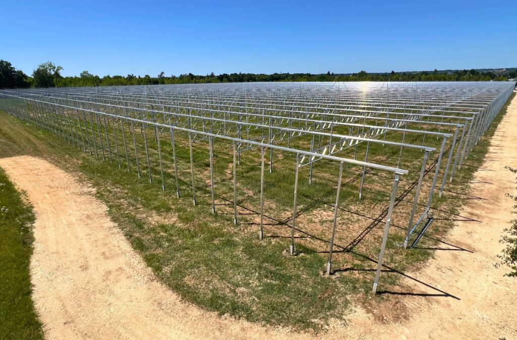 Pierwsze etapy montażu konstrukcji szklarni, z ustawionymi stalowymi słupami w regularnym układzie naw.