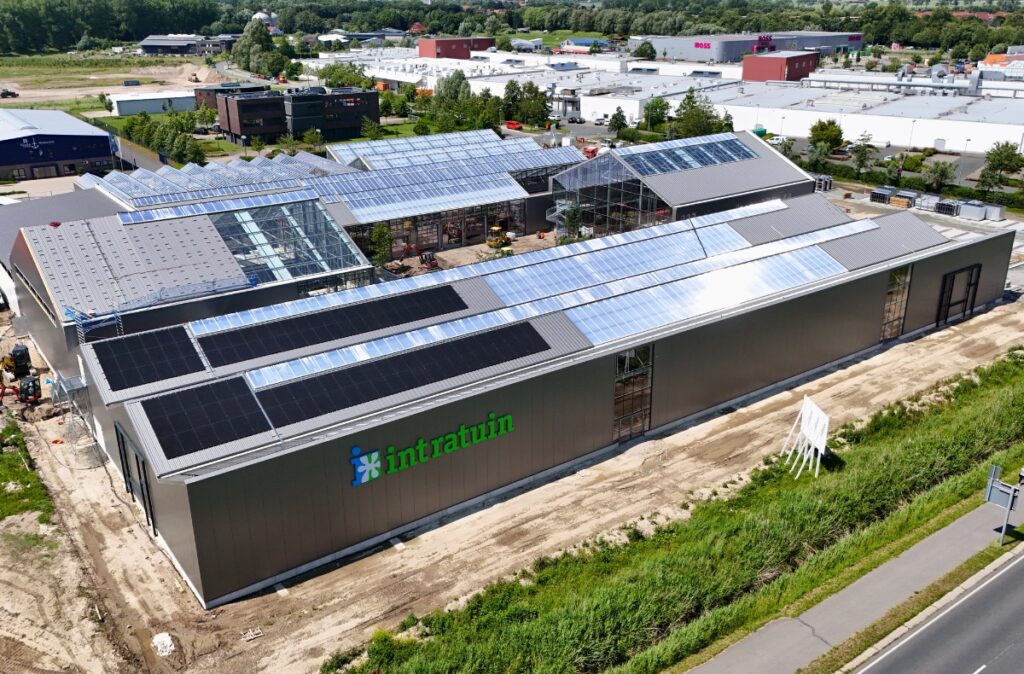 Gotowy kompleks Ostmann Emden z panelami fotowoltaicznymi na dachu i szklarniową konstrukcją handlowo-rekreacyjną.