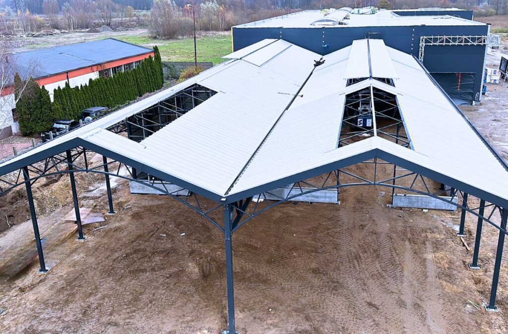 Montaż stalowej konstrukcji wiaty ogrodniczej z układem wielospadowego dachu w początkowej fazie budowy.