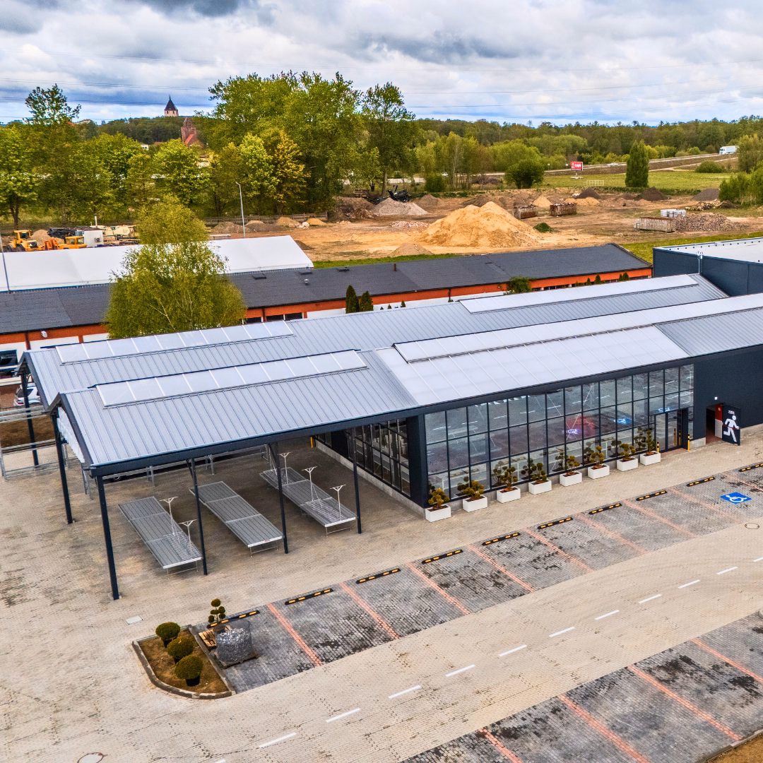 Widok z lotu ptaka na ukończony dział ogrodniczy PSB Mrówka w Sławnie, z przeszkloną fasadą i zadaszoną strefą ekspozycyjną od frontu.