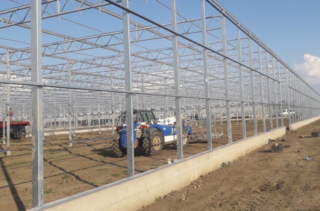 Widok zewnętrzny szklarni szklanej w trakcie montażu konstrukcji nośnej.