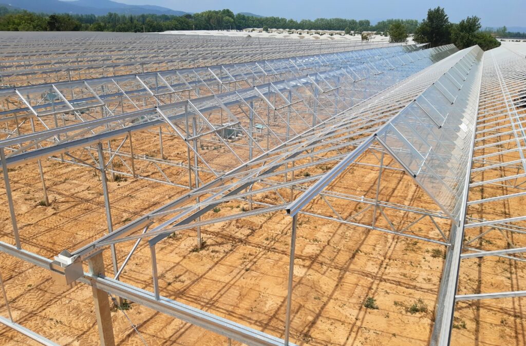 Widok konstrukcji dachowej szklarni w trakcie montażu powierzchni szklanych.