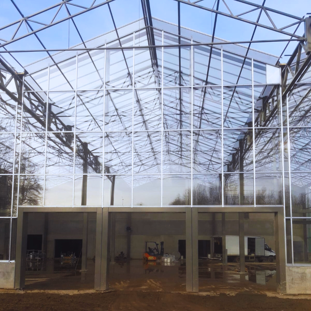 Przeszklona elewacja centrum ogrodniczego Theux – połączenie szklarni z istniejącą halą handlową.