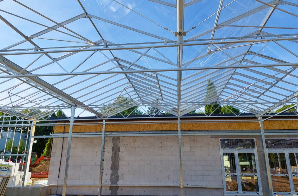 Konstrukcja dachu szklarni z dużymi przeszkleniami zapewniającymi maksymalne doświetlenie.