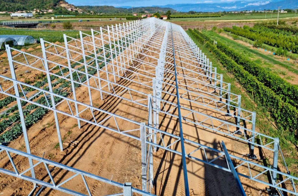Montaż stalowej konstrukcji szklarni w terenie uprawowym.