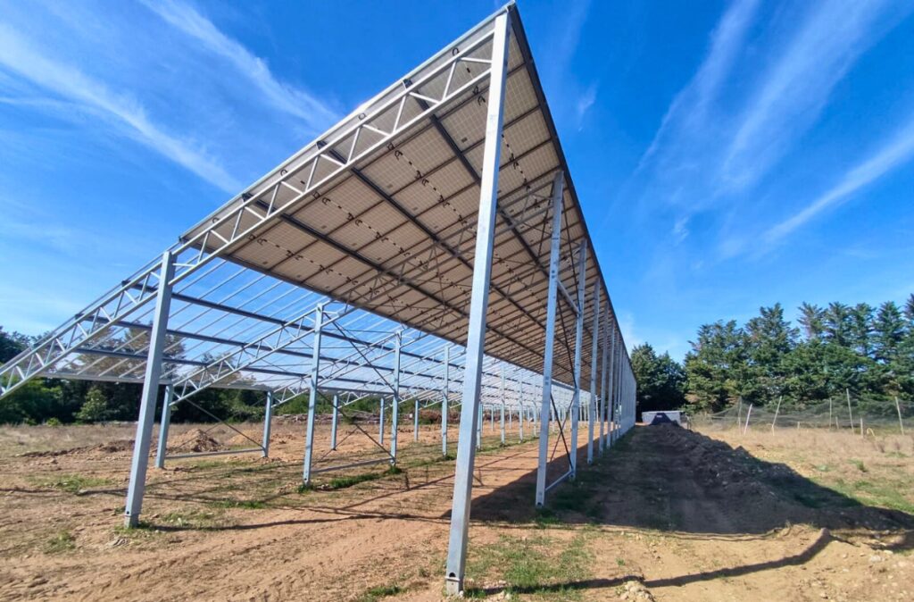 Konstrukcja szklarni z zadaszeniem pod panele fotowoltaiczne na etapie montażu.