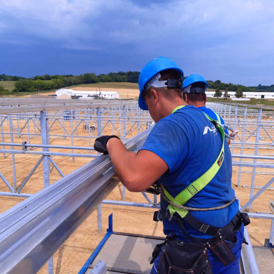 Montaż elementów konstrukcji szklarni produkcyjnej przez zespół montażowy.