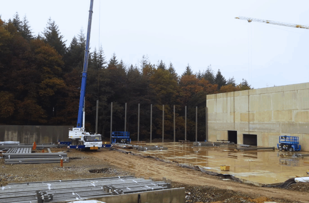 Montaż stalowej konstrukcji centrum ogrodniczego w Theux – prace prowadzone w obniżeniu terenu.