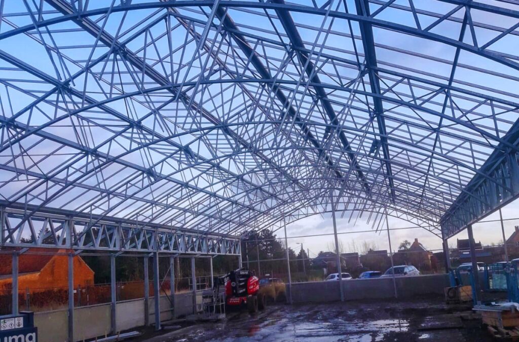 Wnętrze szklarni sprzedażowej – montaż stalowej konstrukcji nośnej przed wykonaniem poszycia.