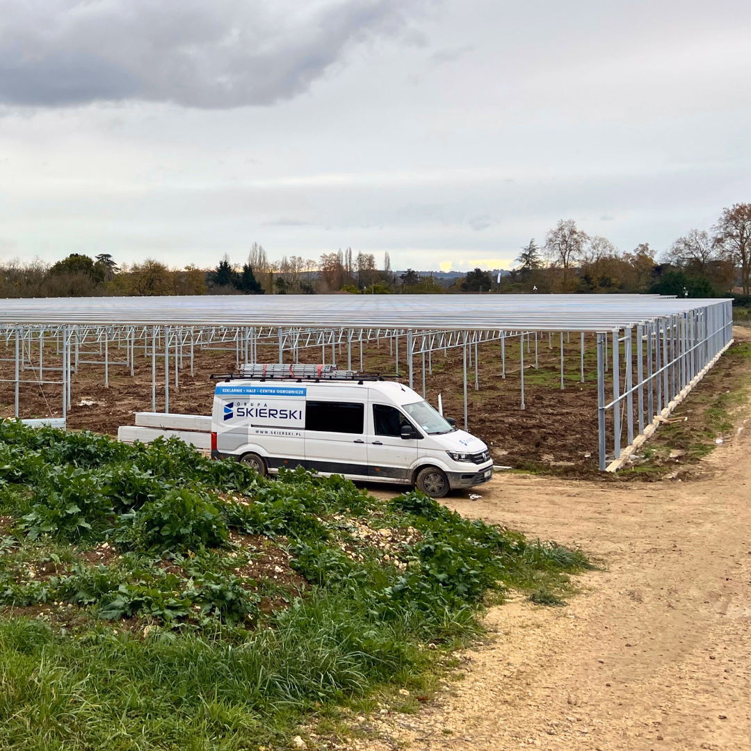 Szklarnia fotowoltaiczna w trakcie montażu konstrukcji nośnej na otwartym terenie.