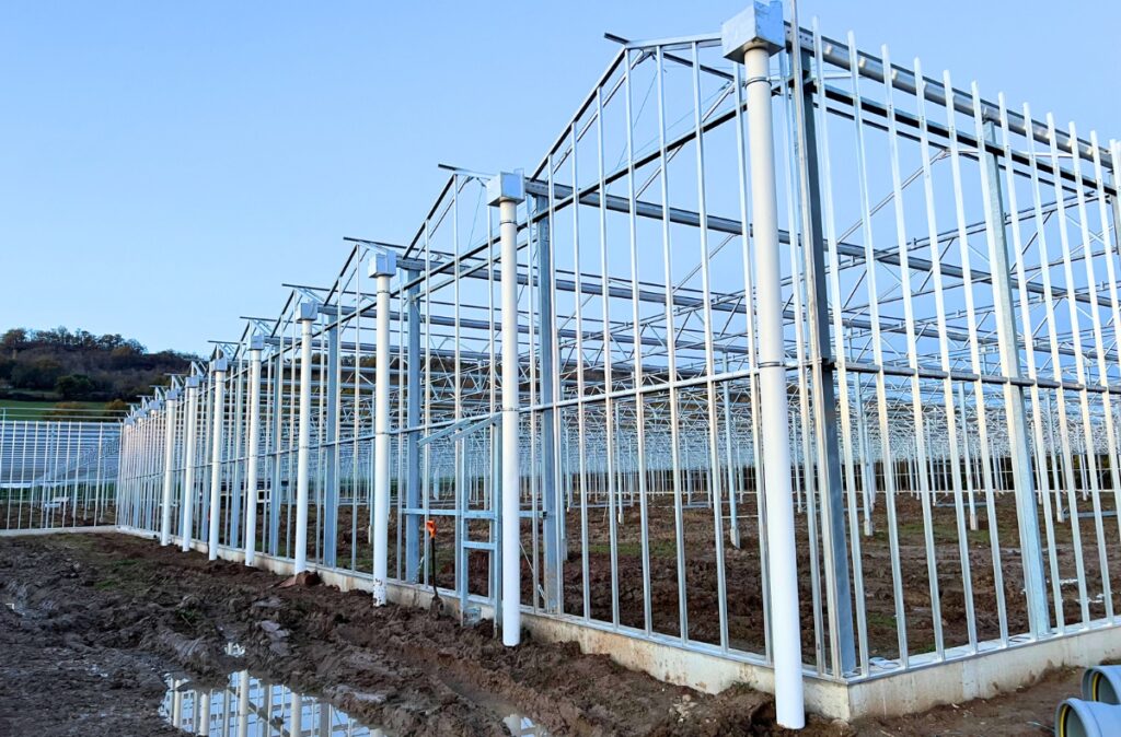 Stalowa konstrukcja szklarni fotowoltaicznej na etapie montażu.