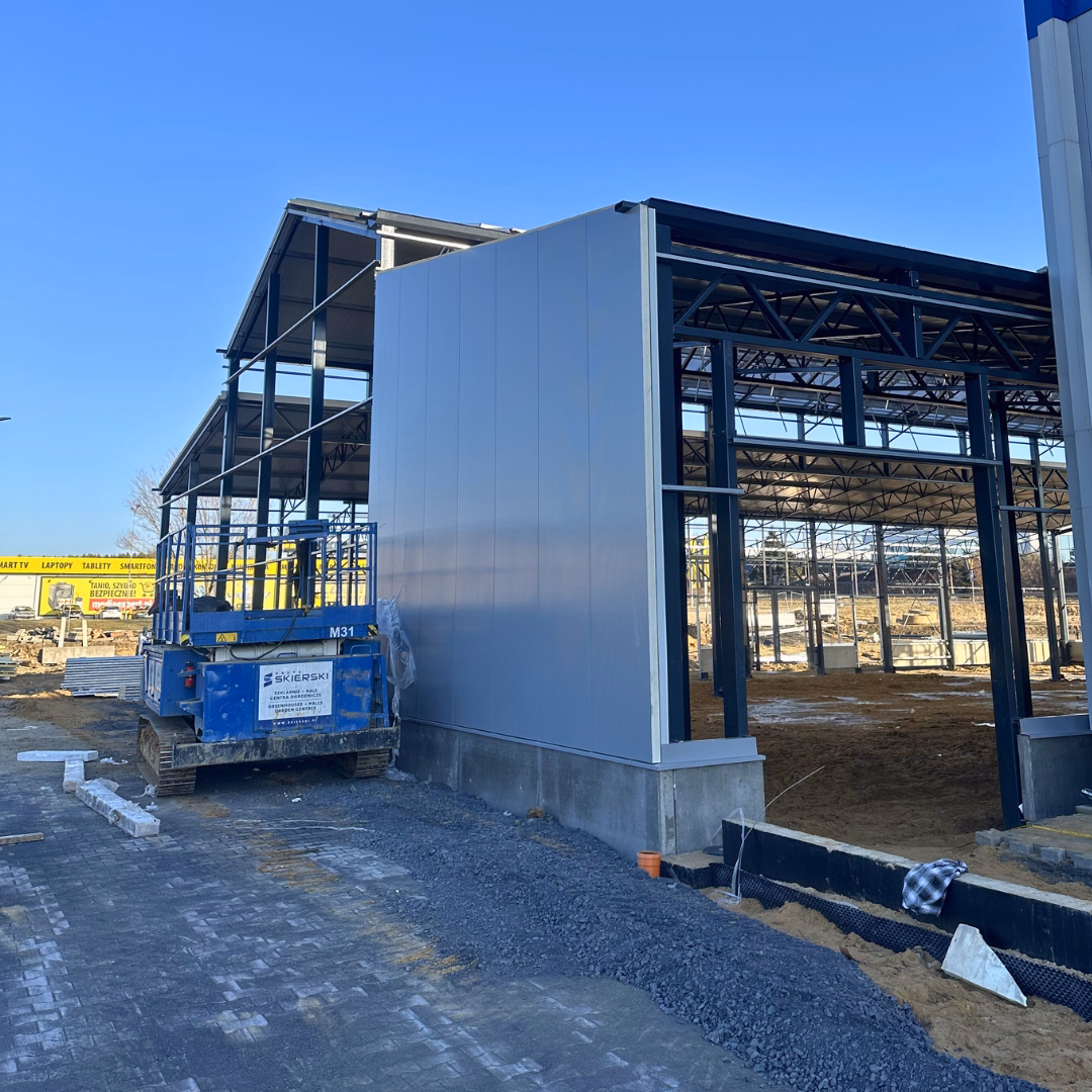 Montaż ściany hali ogrodniczej przy markecie budowlanym.