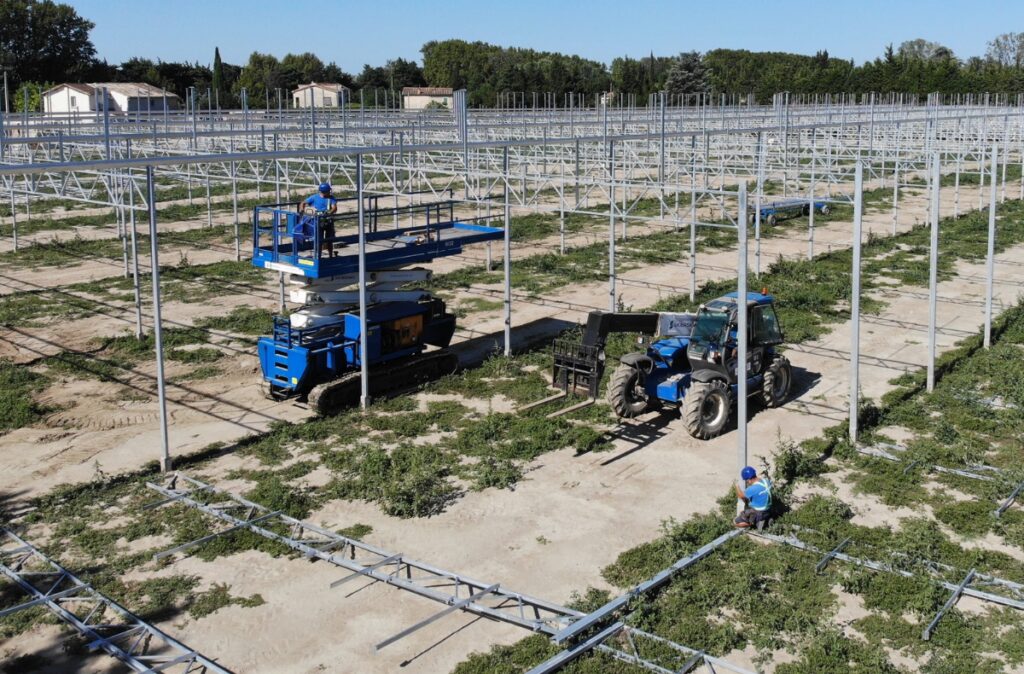 Podnośnik nożycowy i ładowarka teleskopowa podczas montażu konstrukcji szklarni.